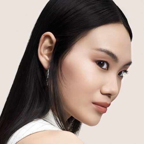 Ritratto di una giovane donna con capelli neri e lunghi, volto di profilo, su sfondo neutro.