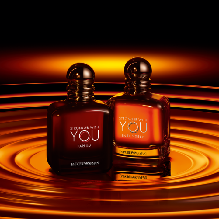 Flaconi Emporio Armani Stronger With You Parfum e Stronger With You Intensely, tonalita ambrate calde su sfondo di onde dorate a spirale