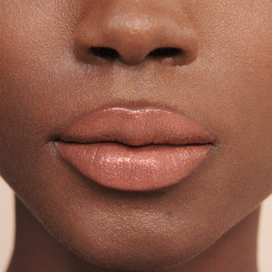 Close-up of a person's lips with a natural nude lipstick finish on a dark skin tone.