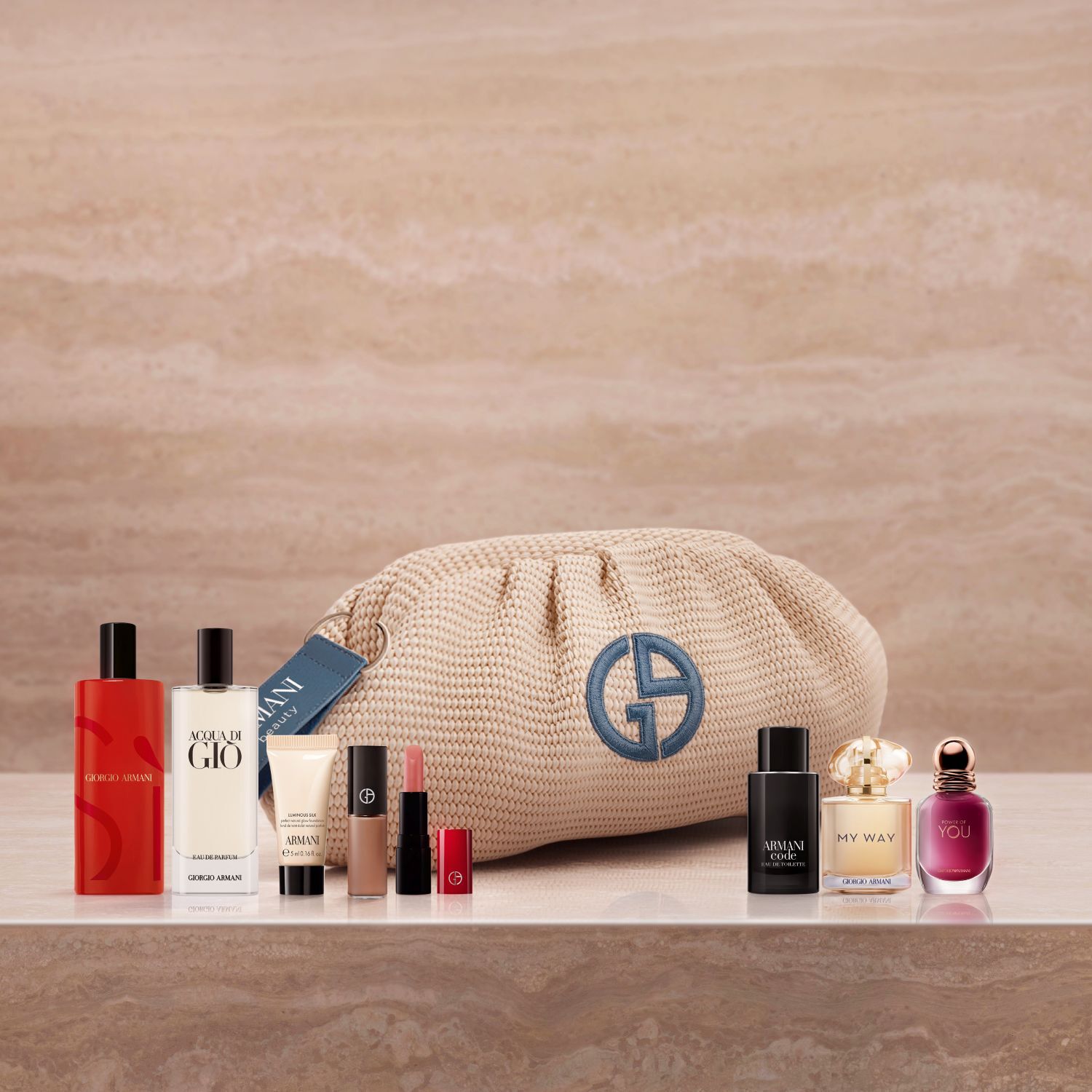 Una lussuosa selezione di icone Armani: fragranze Si, Acqua di Gio e My Way, insieme al fondotinta Luminous Silk e un rossetto. Adagiata su marmo con una pochette beige intrecciata, questa collezione celebra un'eleganza couture senza tempo.