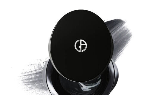 Un prodotto di bellezza con confezione nera e logo in evidenza su uno sfondo grigio.