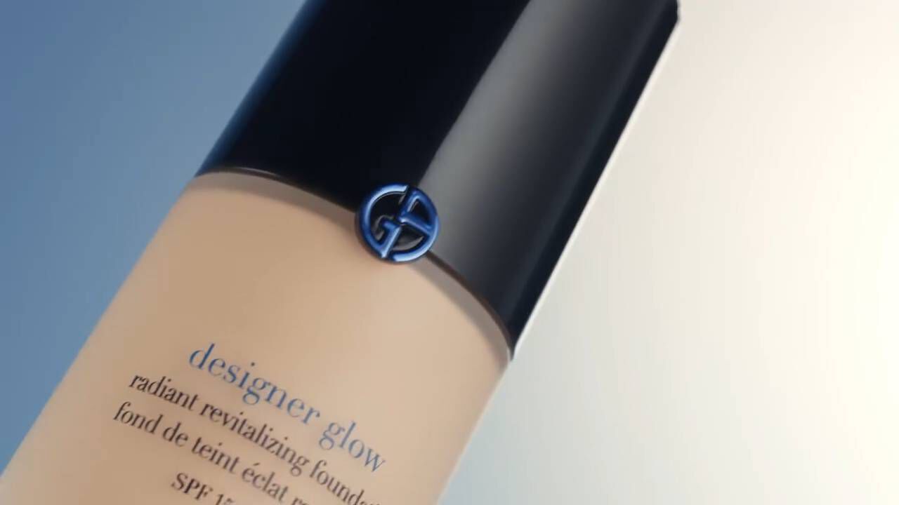 A bottle of designer glow radiant revitalizing foundation with SPF, featuring a sleek black cap and a logo on the front.