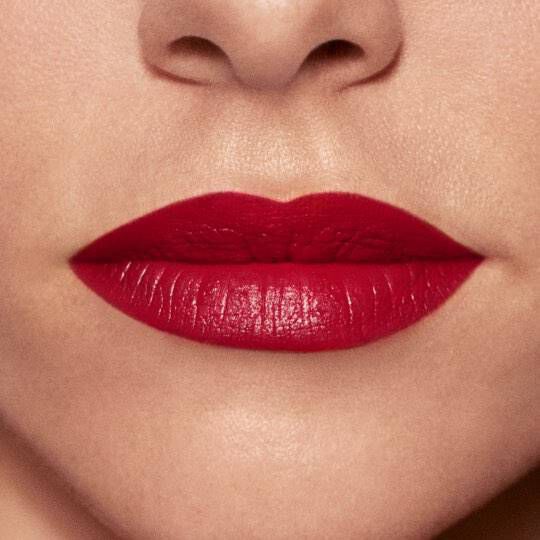 Close-up of a pair of lips with bold red lipstick against smooth skin.
