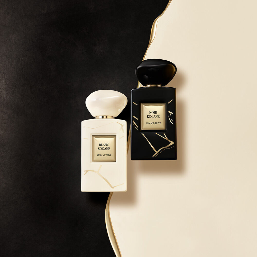 Two elegant perfume bottles, one white and one black, are placed on a minimalistic cream background, showcasing their sophisticated designs.