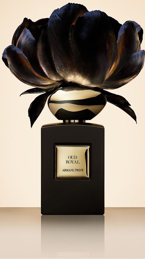Armani/Prive Oud Royal: un flacone nero profondo sormontato da un fiore scuro dai riflessi dorati, che cattura l'essenza reale del legno di Oud e la sacra raffinatezza dei palazzi orientali.