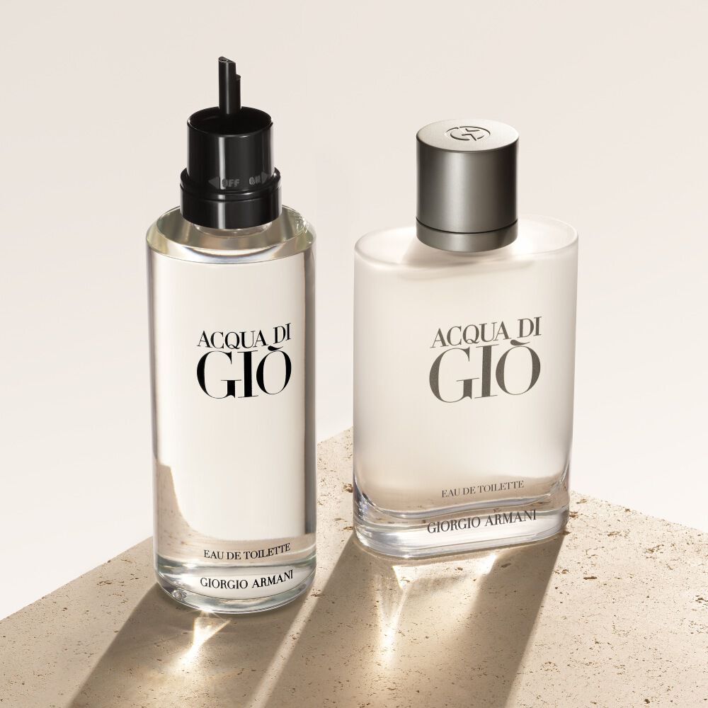 Due flaconi di Acqua di Gio Eau de Toilette, la ricarica a sinistra, sono presentati su uno sfondo beige testurizzato.