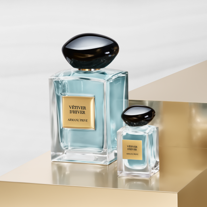 Armani/Prive: un iconico flacone e la sua elegante miniatura svelano un'essenza verde pallido. Su un piedistallo dorato, celebrano il sereno equilibrio del te e il lusso artigianale couture della Maison.