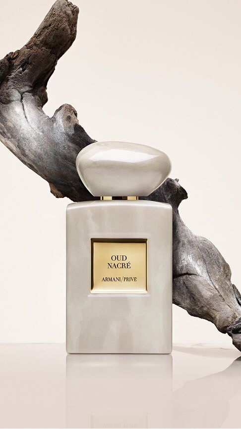 Armani/Prive Oud Nacre: un flacone dai riflessi perlati e iridescenti davanti a un legno scolpito, che cattura l'intramontabile nobilta dell'Oud in una scia di assoluta purezza ed eleganza.