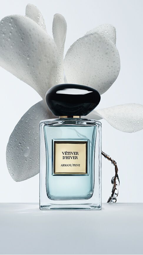 Armani/Prive Vetiver d'Hiver: un flacone che svela un nettare azzurro, incorniciato da delicati petali bianchi bagnati di rugiada, che evoca la freschezza cristallina e luminosa dell'inverno.