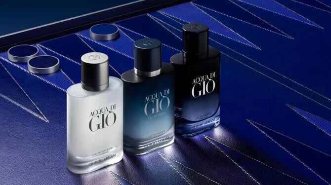 Three Armani Acqua di Gio bottles displayed on a textured blue Blackgammon surface, highlighting the gradient design and the brand’s aquatic, modern fragrance range.