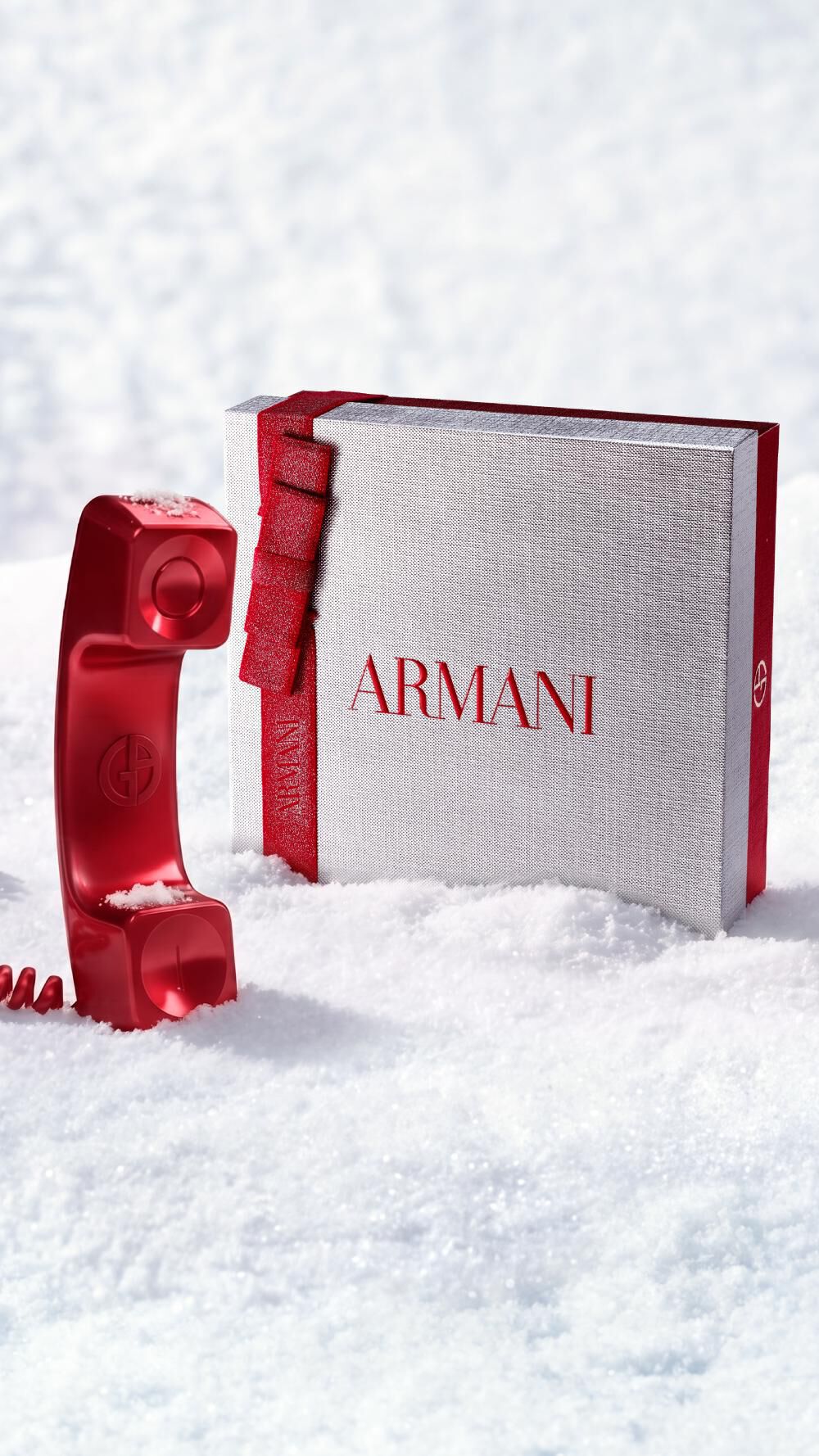 Confezione regalo di Natale Armani Beauty con un telefono rosso che richiama il servizio clienti, in un paesaggio innevato.