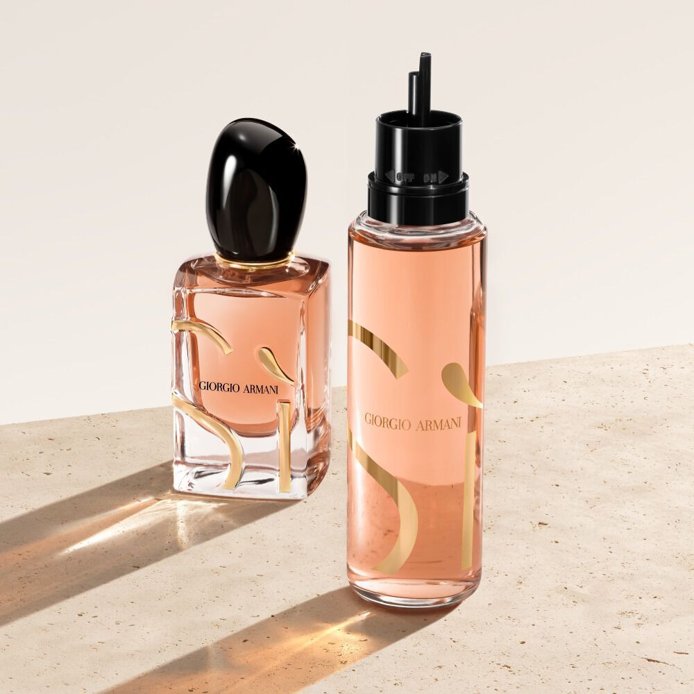  Due flaconi di Giorgio Armani Si Eau de Parfum su una superficie beige. Il flacone a sinistra e il classico flacone del profumo Si, mentre quello a destra e un flacone di ricarica dall'aspetto piu traslucido e color pesca.