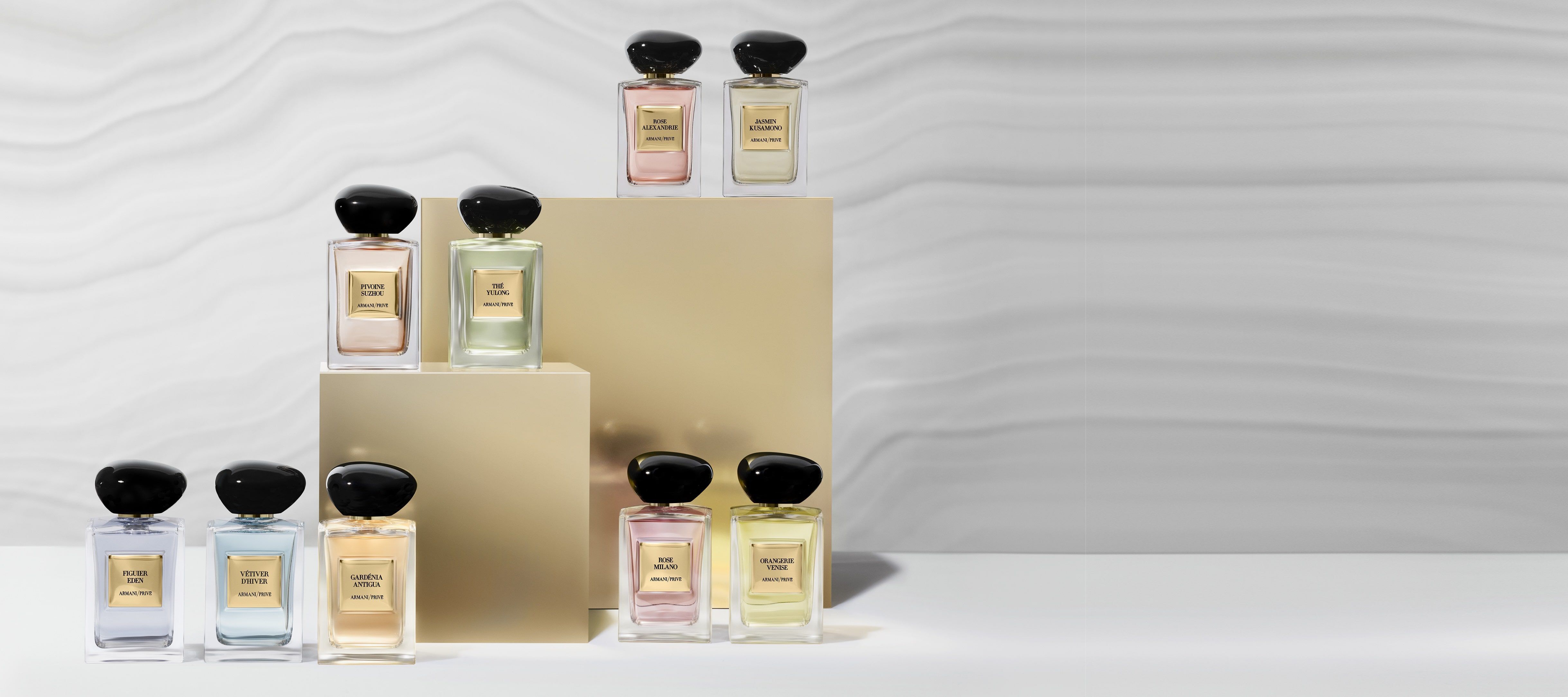 A collection of elegantly designed perfume bottles displayed on golden pedestals, set against a softly textured background.
