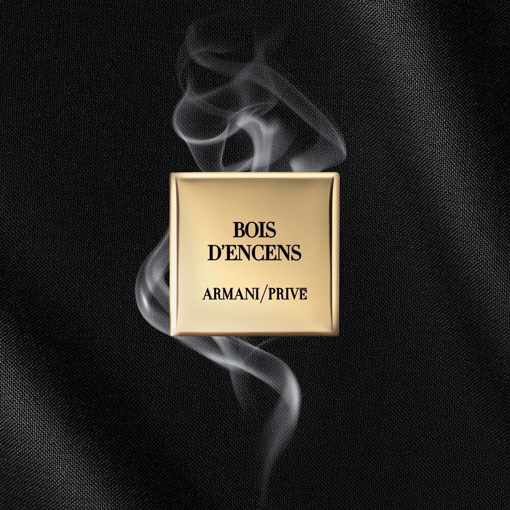A gold square label with the text "BOIS D'ENCENS" and "ARMANI/PRIVE" on a dark, textured background with wisps of smoke.