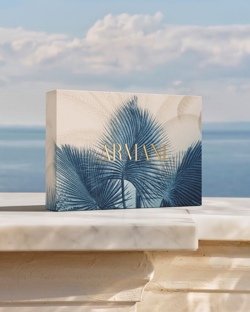 Un raffinato set regalo Armani con motivo botanico blu, su una base di marmo davanti al mare. Un omaggio alla collezione "Armani Mare", che unisce artigianalita couture ed eleganza solare per un rito di bellezza unico.