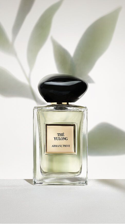 Armani/Prive The Yulong: un flacone con un'essenza verde pallido, su uno sfondo minimalista di ombre di foglie, che incarna l'equilibrio sereno tra te affumicato e te verde.