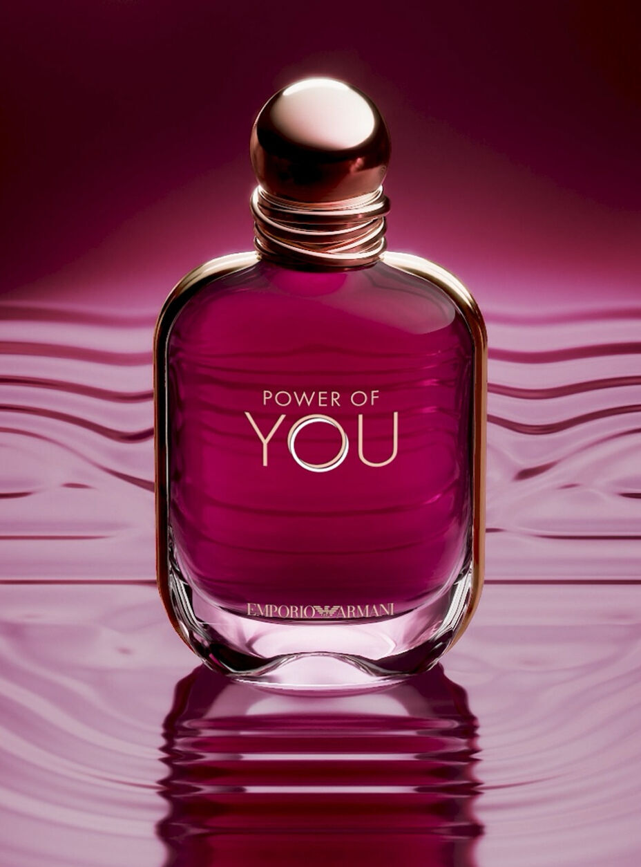  Una pubblicita ravvicinata della boccetta di profumo "Power of You" di Emporio Armani. La boccetta in vetro tonalita rubino e posta al centro di una superficie liquida magenta scuro riflettente che mostra lievi increspature. La boccetta presenta un tappo dorato arrotondato e le scritte "POWER OF YOU" ed "EMPORIO ARMANI" stampate in oro. Lo sfondo e un morbido gradiente sfumato di rosa intenso e viola. In basso, un testo bianco recita: "Presentazione di un'iconica nuova boccetta: un gioiello dalle tonalita rubino", seguito dal link "SCOPRI" e da un'icona di pausa.