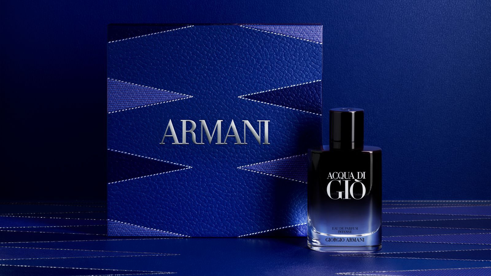 Flacone di profumo Giorgio Armani "Acqua di Gio" con una scatola regalo Armani blu testurizzata.
