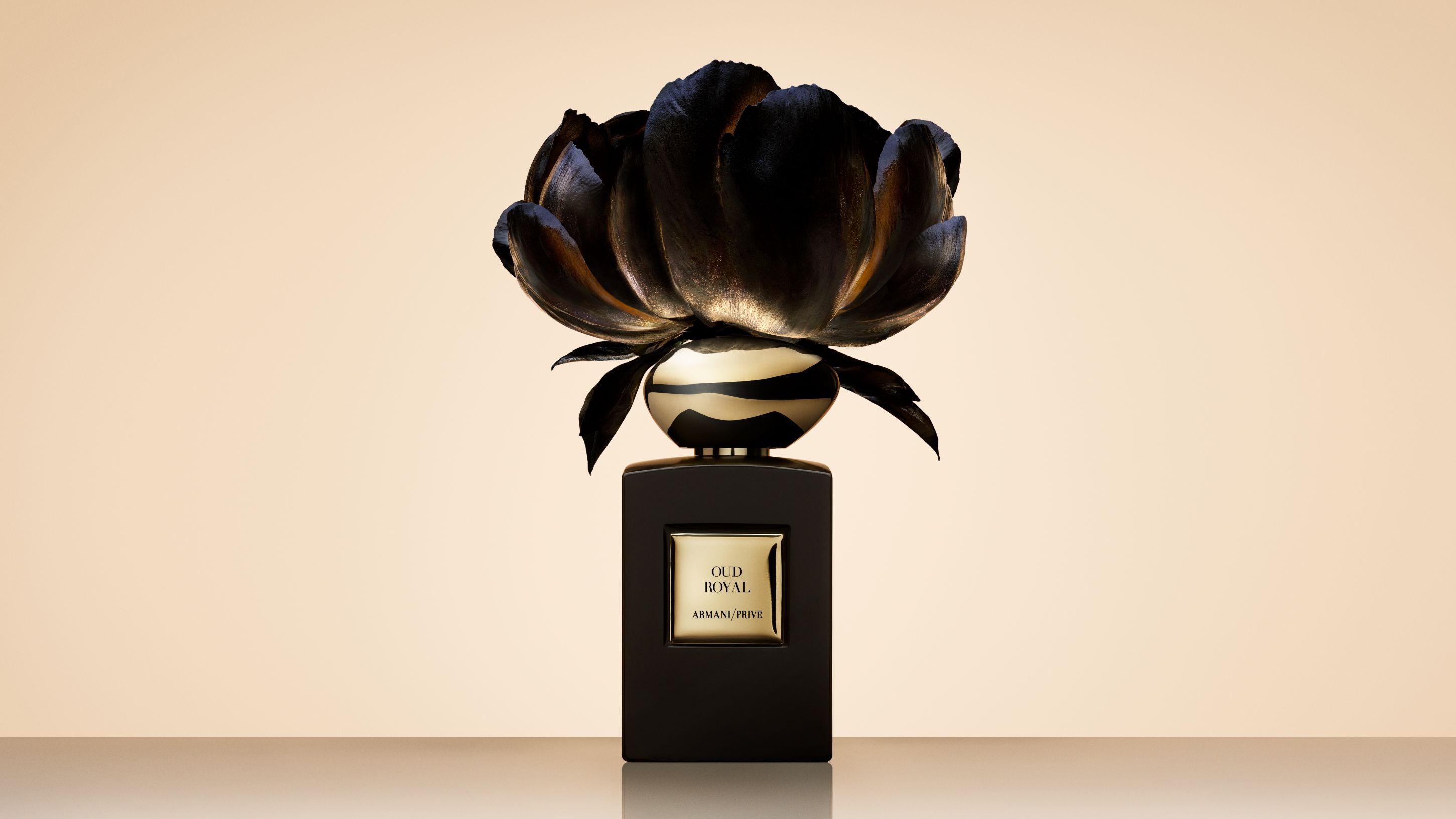 Flacone di profumo Armani/Prive Oud Royal sormontato da un grande fiore nero artistico.