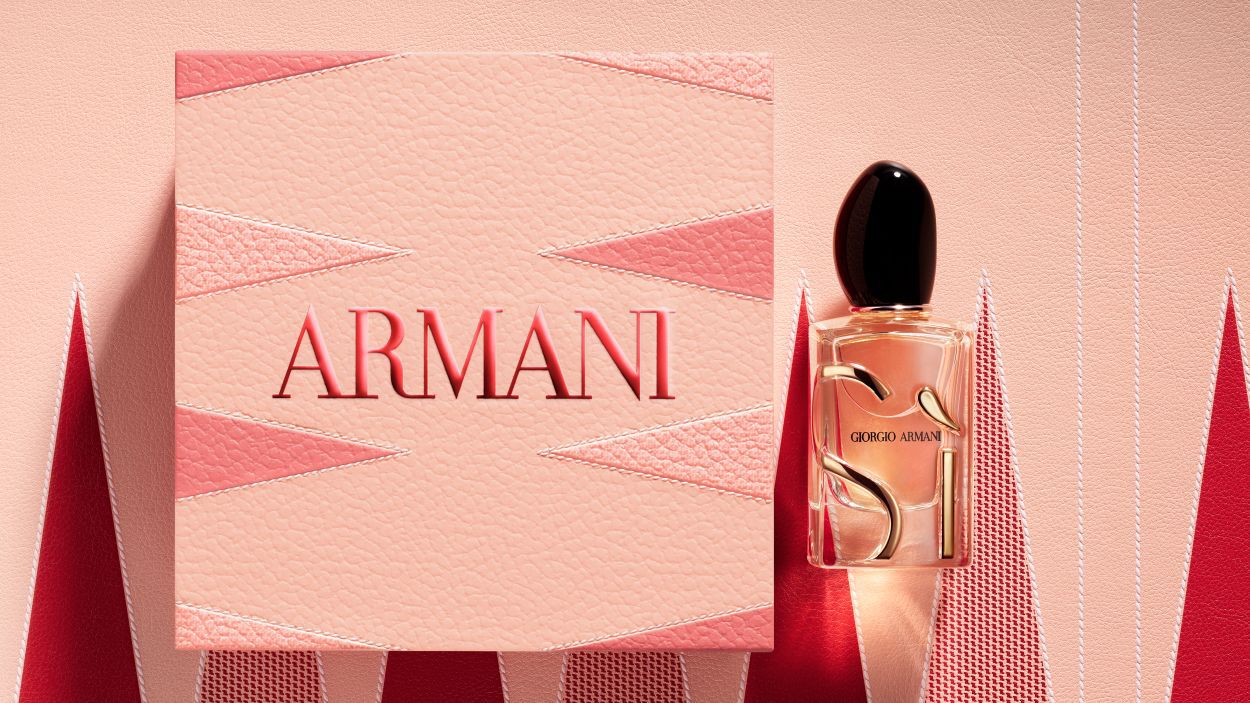Flacone di profumo Giorgio Armani "Si" accanto a una grande scatola regalo Armani rosa testurizzata.