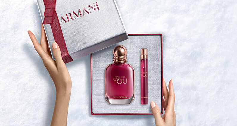Flacone di profumo Giorgio Armani "Si" accanto a una grande scatola regalo Armani rosa testurizzata.