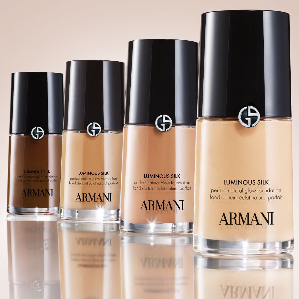 A row of multiple Armani Beauty LUMINOUS SILK FOUNDATION bottles in varying shades, from light to dark, demonstrating the reimagined and expanded 44-shade range designed for an even better color match.