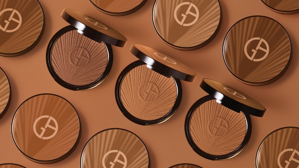 Tre cialde di terra abbronzante Giorgio Armani su uno sfondo colorato, con il logo distintivo evidenziato.