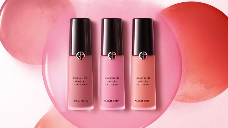 Tre flaconi di blush liquido 'Luminous Silk' di Giorgio Armani, su uno sfondo sfumato di colori pastello.