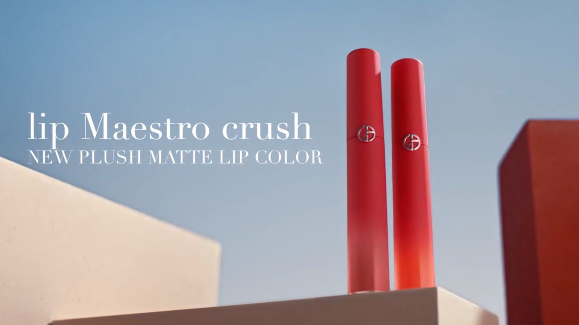 Two vibrant red lip color tubes set against a clear blue sky, showcasing the new Lip Maestro Crush collection.