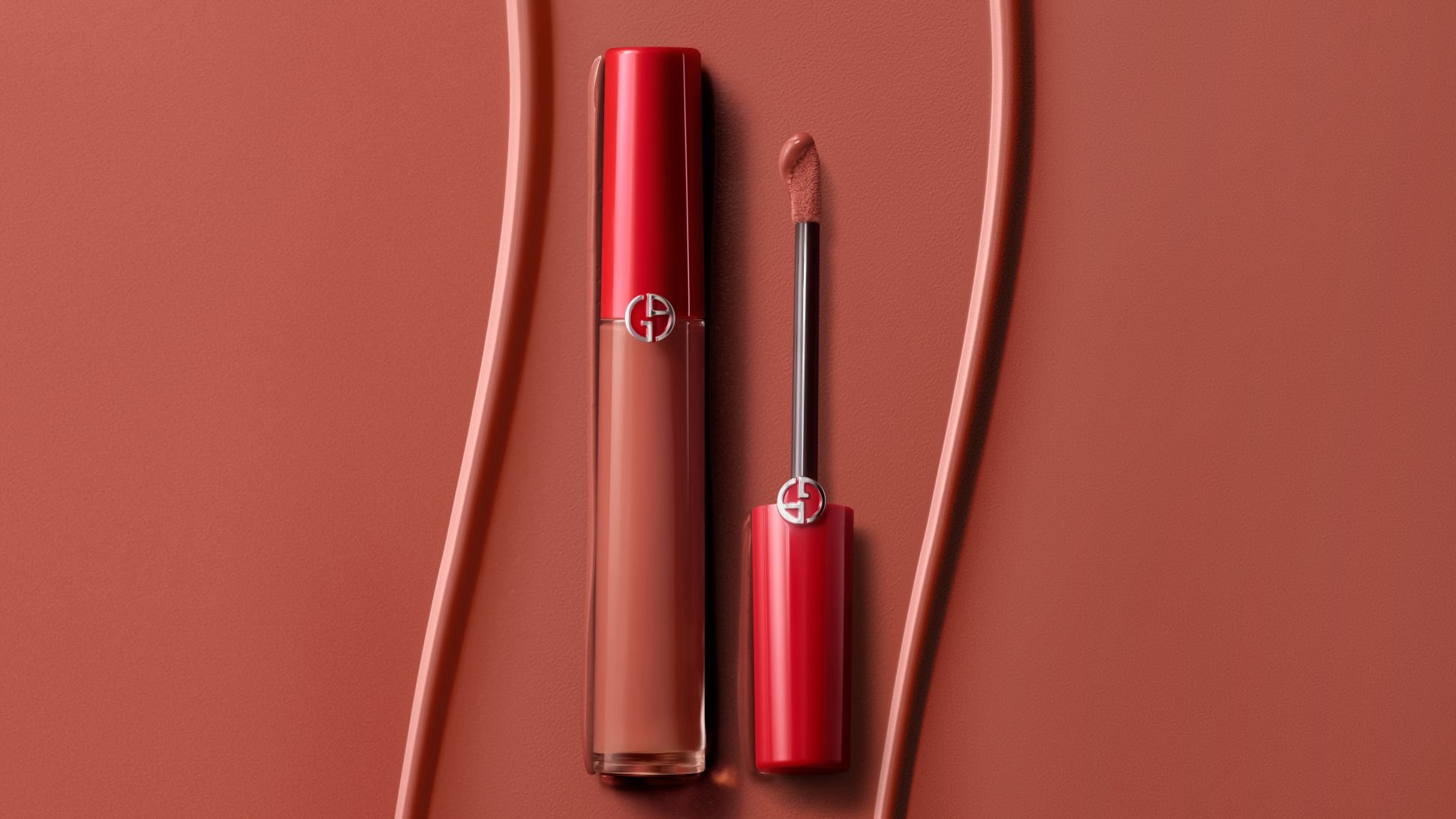 Rossetto liquido Giorgio Armani con applicatore su sfondo terracotta texturizzato.