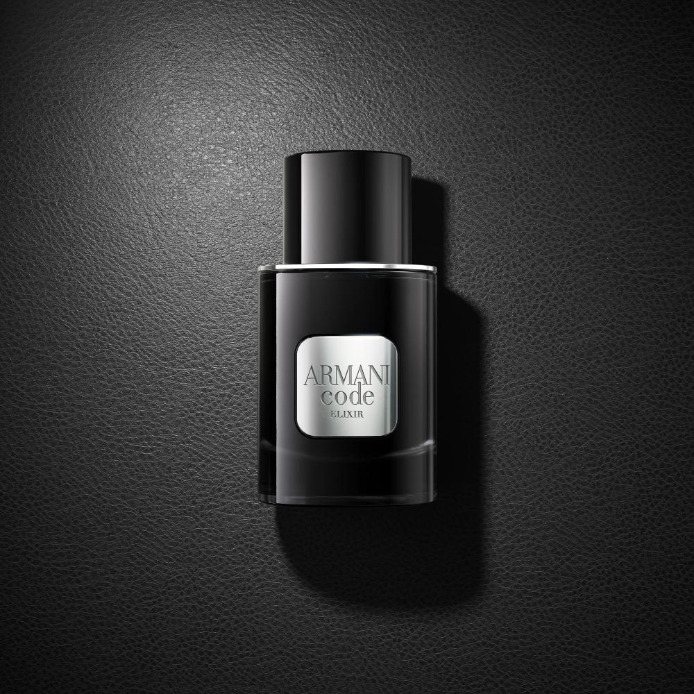 Un flacone nero del profumo Armani Code Elixir poggia elegantemente su una superficie nera coordinata, creando un sofisticato look monocromatico.